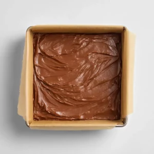 Cottage cheese fudge mixture spread in a square baking dish lined with parchment paper